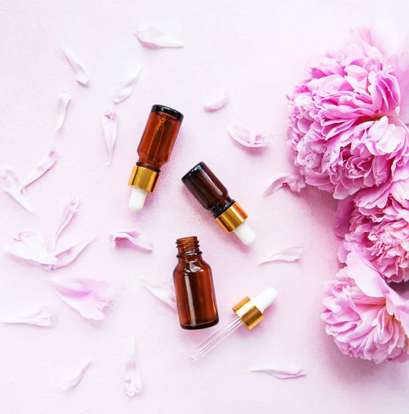 Aromatherapy essentials oils and pink peonies — Stock Photo, Image