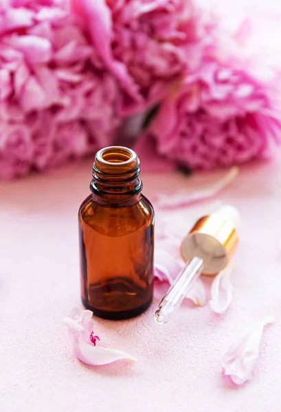 Aromatherapy essentials oils and pink peonies — Stock Photo, Image