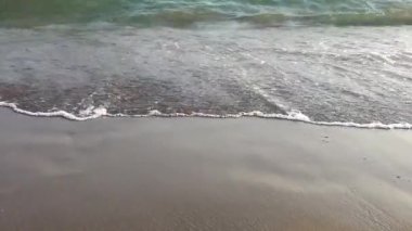 Kumsaldaki ayak izlerini yıkanan deniz dalgalarının yavaş çekim görüntüleri