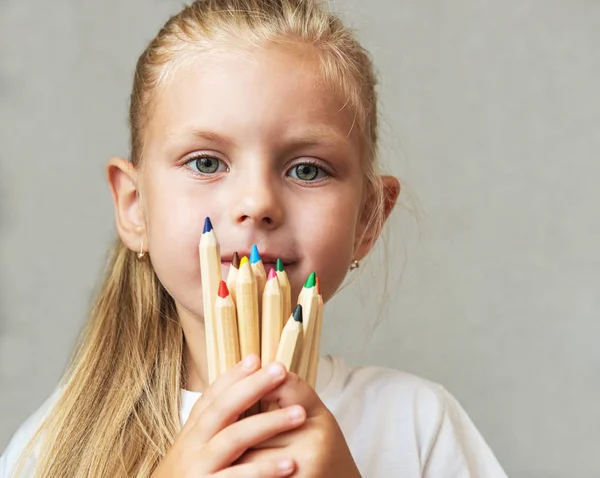 Meisje houdt potloden voor gezicht — Stockfoto