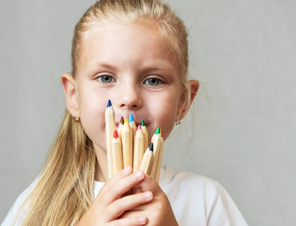 Meisje houdt potloden voor gezicht — Stockfoto