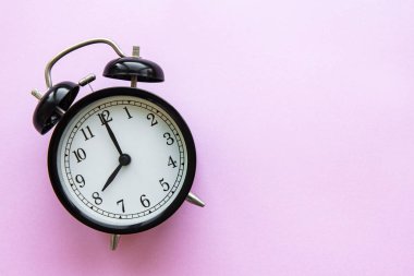 Pembe arka planda izole edilmiş siyah bir çalar saat