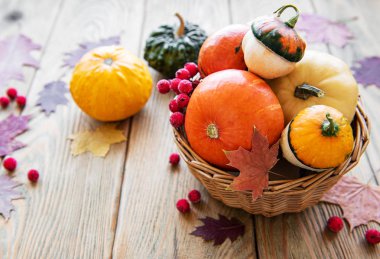 Tahta bir masada üzerinde balkabağı olan sepet.