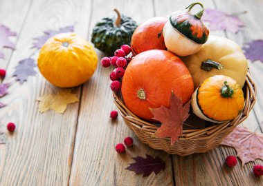 Tahta bir masada üzerinde balkabağı olan sepet.