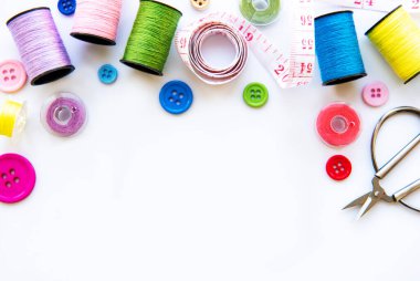 Beyaz arka planda aksesuar ve kumaş dikmek. Dikiş iplikleri, iğneler, iğneler, kumaşlar, düğmeler ve dikiş santimetresi. Üst manzara, düz uzanma.