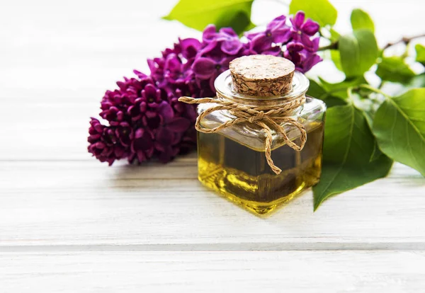 Spa oil with lilac flowers. Bottle with aroma oil  and lilac flowers on wooden background.