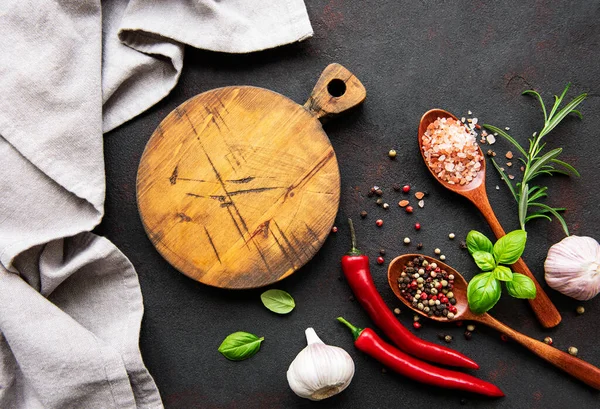 Tahtadaki üst manzara ve koyu beton arka plandaki baharatlar. Düz yatıyordu. 