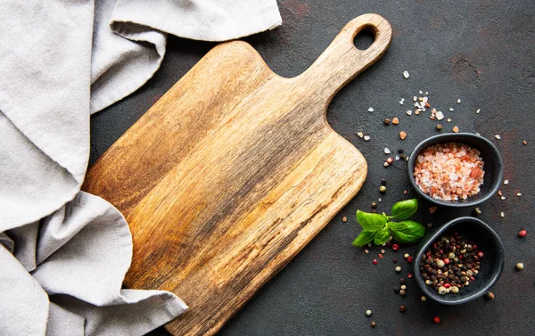 Kesme tahtası, baharatlar ve koyu beton arka plan.