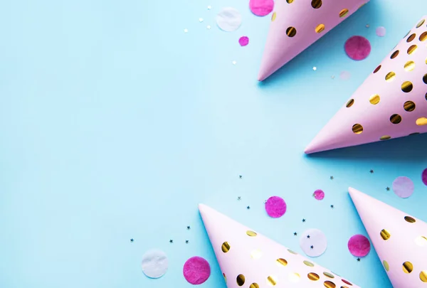 Happy birthday or party background.  Flat Lay with birthday hats and confetti  on blue background. Top View.  Copy space.