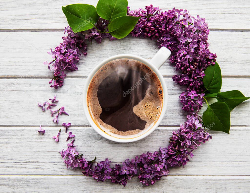 Lilac flowers on a table in the shape of a circle top view on a cup of coffee