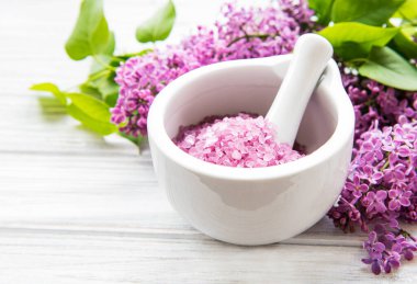 Beyaz ahşap bir arka planda havan ve leylak çiçekli spa deniz tuzu