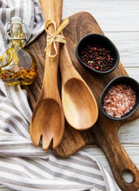 Eski mutfak gereçleri. Tahta kaşıklar, tahta kesme tahtası, beyaz ahşap masa üzerinde peçete ve baharatlar. Üst görünüm