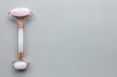 Güzellik masajı terapisi için yeşim yüz silindiri. Gri arkaplanda düz uzandı