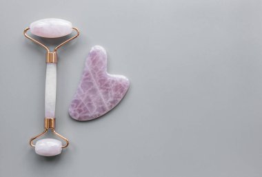 Güzellik masajı terapisi için yeşim yüz silindiri. Gri arkaplanda düz uzandı