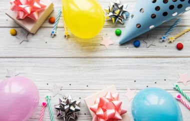 Mutlu yıllar ya da parti geçmişi. Doğum günü şapkaları, konfeti ve beyaz ahşap arka planda kurdeleler. Üst Manzara. Boşluğu kopyala.