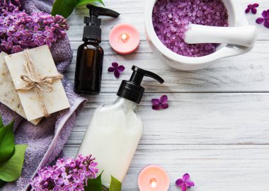 Leylak çiçekli spa seti. Kasede deniz tuzu, aroma yağı şişeleri ve ahşap arka planda mumlar.. 