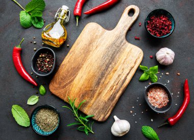 Tahtadaki üst manzara ve koyu beton arka plandaki baharatlar. Düz yatıyordu. 