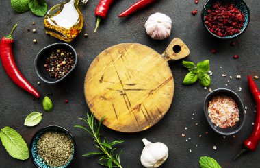 Tahtadaki üst manzara ve koyu beton arka plandaki baharatlar. Düz yatıyordu. 