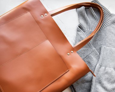 Kahverengi deri kadın çantası, gri örgü süveter, üst manzara, düz yatak. Modaya uygun kadın aksesuarları. Sonbahar Moda Konsepti. 