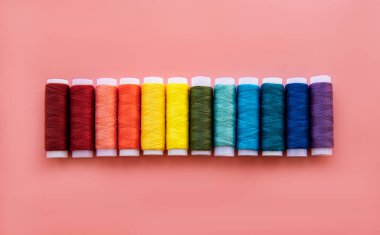 Pembe arka planda gökkuşağının renklerinde iplik makaraları, düz yatıyordu.
