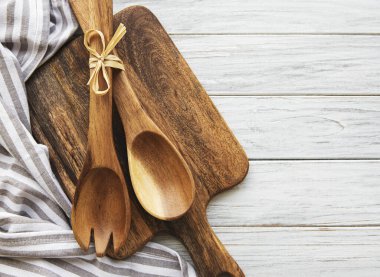 Eski mutfak gereçleri. Tahta kaşıklar, tahta kesme tahtaları, beyaz tahta masanın üzerine peçete. Üst görünüm