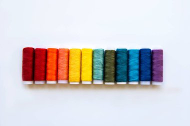 Beyaz bir arka planda gökkuşağının renklerinde iplik makaraları, düz yatıyordu