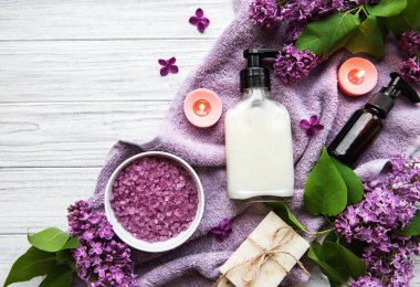 Leylak çiçekli spa seti. Kasede deniz tuzu, aroma yağı şişeleri ve ahşap arka planda mumlar.. 