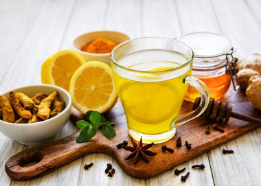 Beyaz ahşap arka planda zerdeçal, zencefil, limon ve bal içeren enerji toniği
