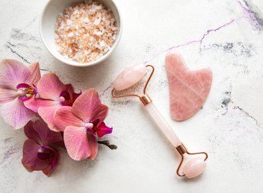 Orkide çiçekli doğal organik SPA kozmetik seti. Düz banyo tuzu, yüz silindiri, mermer arka planda orkide çiçekleri. Cilt bakımı, güzellik tedavi konsepti