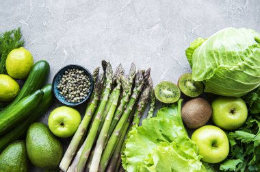 Sağlıklı vejetaryen gıda konsepti, detoks diyeti için taze yeşil gıda seçimi, elma, salatalık, kuşkonmaz, avokado, limon, beton arka planda salata üstü görünümü.