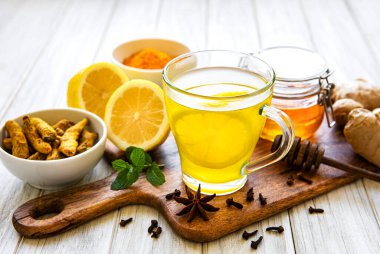 Beyaz ahşap arka planda zerdeçal, zencefil, limon ve bal içeren enerji toniği