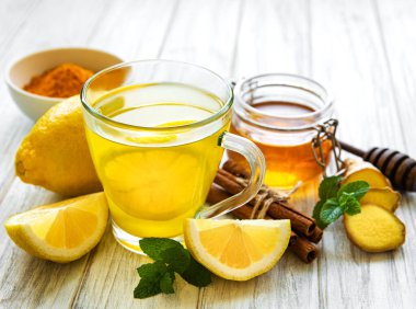 Beyaz ahşap arka planda zerdeçal, zencefil, limon ve bal içeren enerji toniği