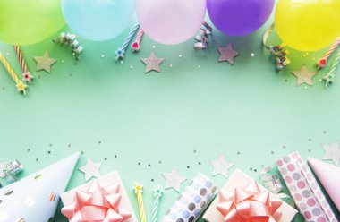 Mutlu yıllar ya da parti geçmişi. Doğum günü balonları, konfeti ve pastel yeşil arka planda kurdeleler. Üst Manzara. Boşluğu kopyala.