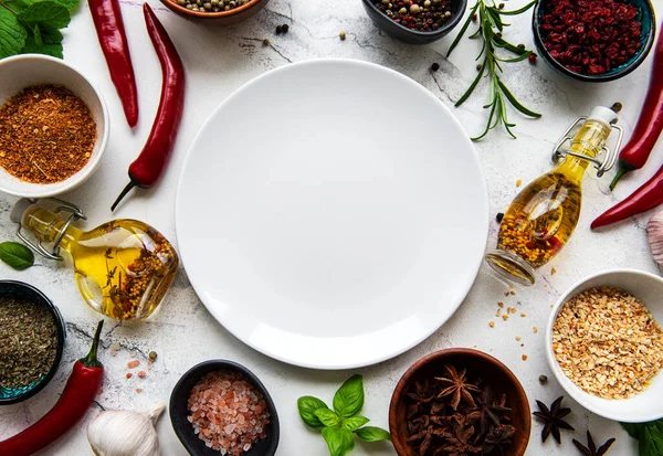 Empty  plate and frame of spices, herbs and vegetables on a white marble background. Top view, flat lay.