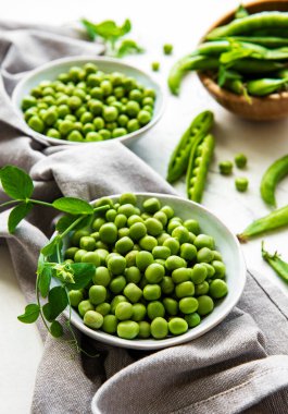 Masanın üstünde taze kabuklu yeşil bezelyeler var, üst ya da düz.