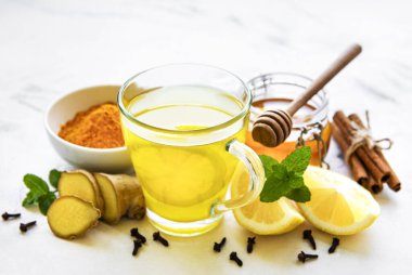 Beyaz ahşap arka planda zerdeçal, zencefil, limon ve bal içeren enerji toniği