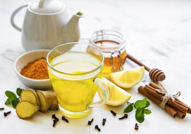 Beyaz ahşap arka planda zerdeçal, zencefil, limon ve bal içeren enerji toniği
