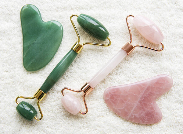 Нефритовые катки для косметического массажа лица. Плоский лежал на витиевом инструментальном фоне