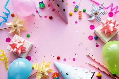 Pembe pastel arka planda pano ve renkli dekorasyonlar. Düz yerde, üst tarafta. Doğum günü geçmişi, tatil kavramı.
