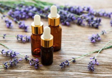Eski ahşap arka planda lavanta yağı ve taze lavanta şişeleri.