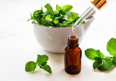 Nane yağı ve beyaz mermer zemin üzerinde taze nane şekeri.