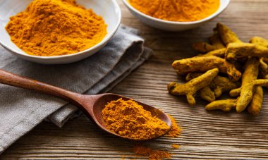  Tahta zemin üzerinde sarı zerdeçal tozu ve kuru kökler.