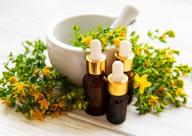 St johns Wort yağları, ve eski ahşap bir masa üzerinde bir havan topu taze otlar