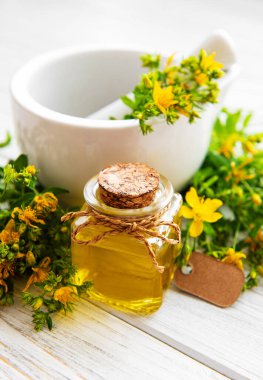 St johns Wort yağları, ve eski ahşap bir masa üzerinde bir havan topu taze otlar