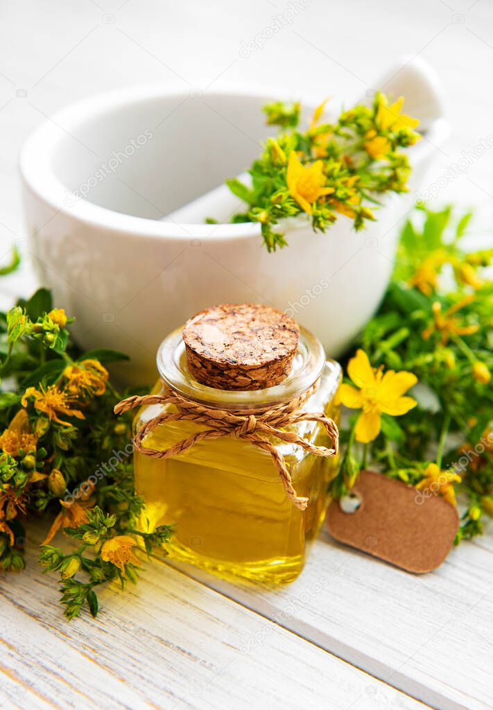 St johns wort oils, and  fresh herbs in a mortar on a old wooden table