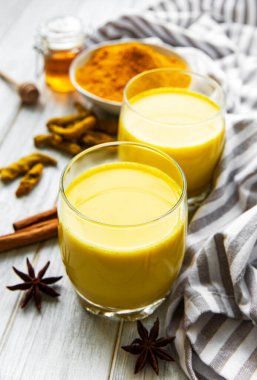 Sarı zerdeçal latte. Beyaz mermer zemin üzerinde tarçın, zerdeçal, zencefil ve bal içeren altın süt.