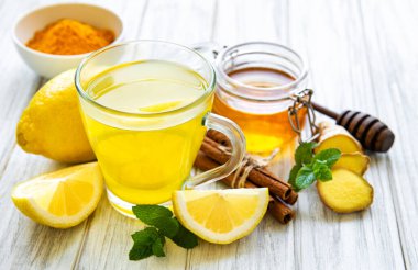 Beyaz ahşap arka planda zerdeçal, zencefil, limon ve bal içeren enerji toniği