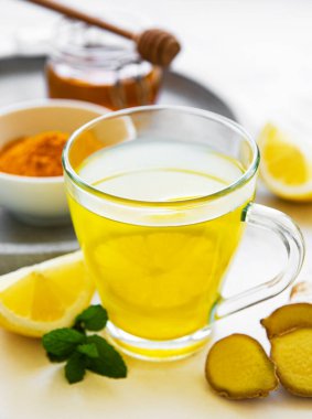 Beyaz mermer bir zemin üzerinde zerdeçal, zencefil, limon ve bal içeren enerji toniği