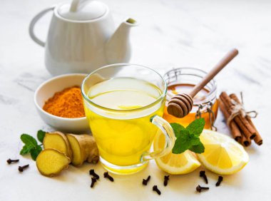 Beyaz ahşap arka planda zerdeçal, zencefil, limon ve bal içeren enerji toniği