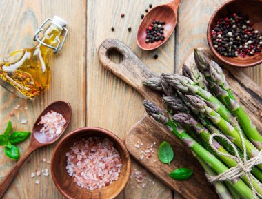 Köy ahşap bir masada taze yeşil kuşkonmaz demeti.